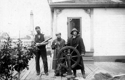 Three men standing on a porch with a steering wheel.