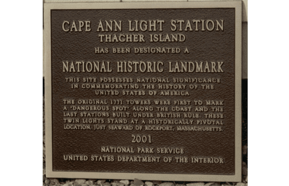 A plaque is shown in front of the entrance to cape ann light station.