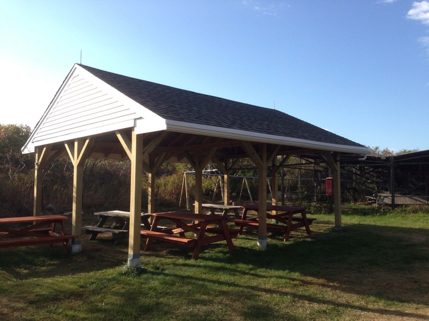 A large wooden structure with picnic tables underneath it.