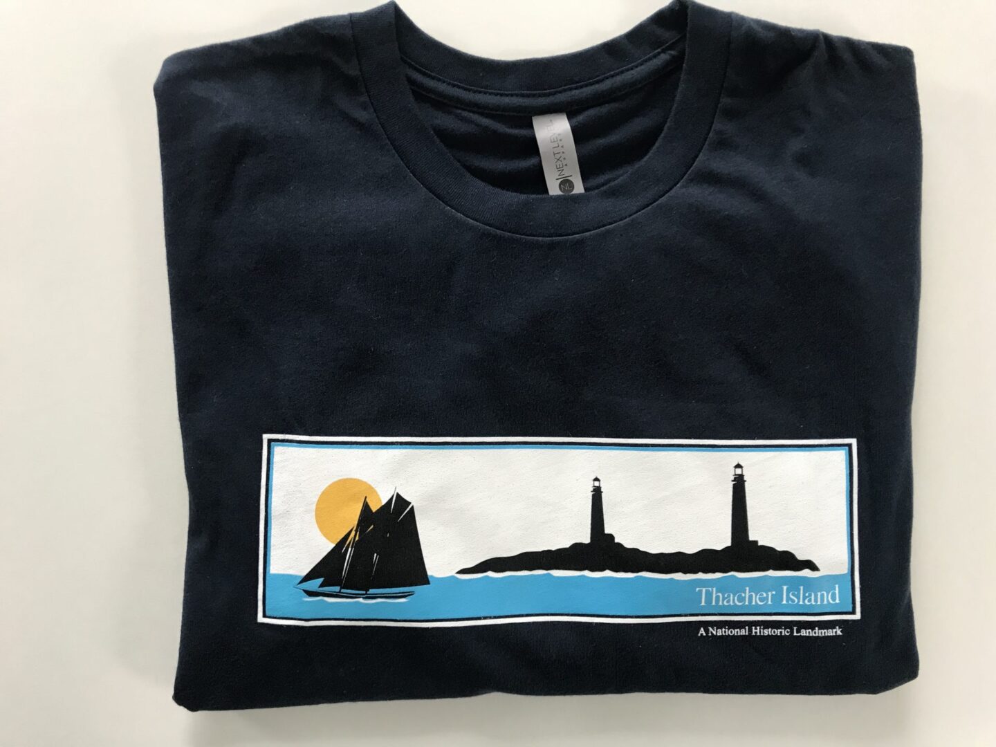 A black t-shirt with a picture of a boat and lighthouse.