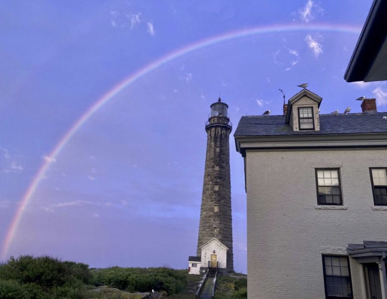 A rainbow over the top of a lighthouse.