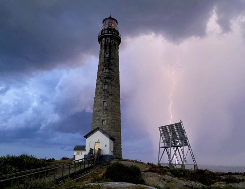 A lighthouse with a storm coming in from the sky.