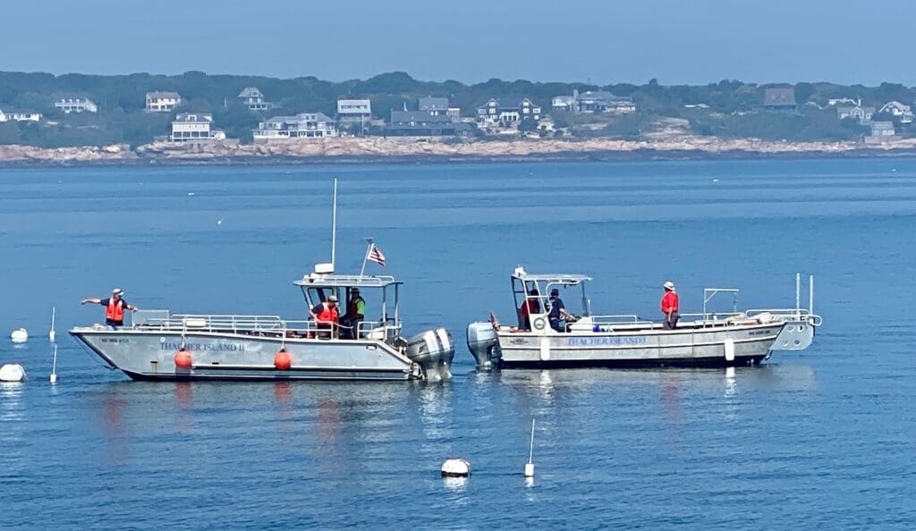 Two boats are in the water near a shore.